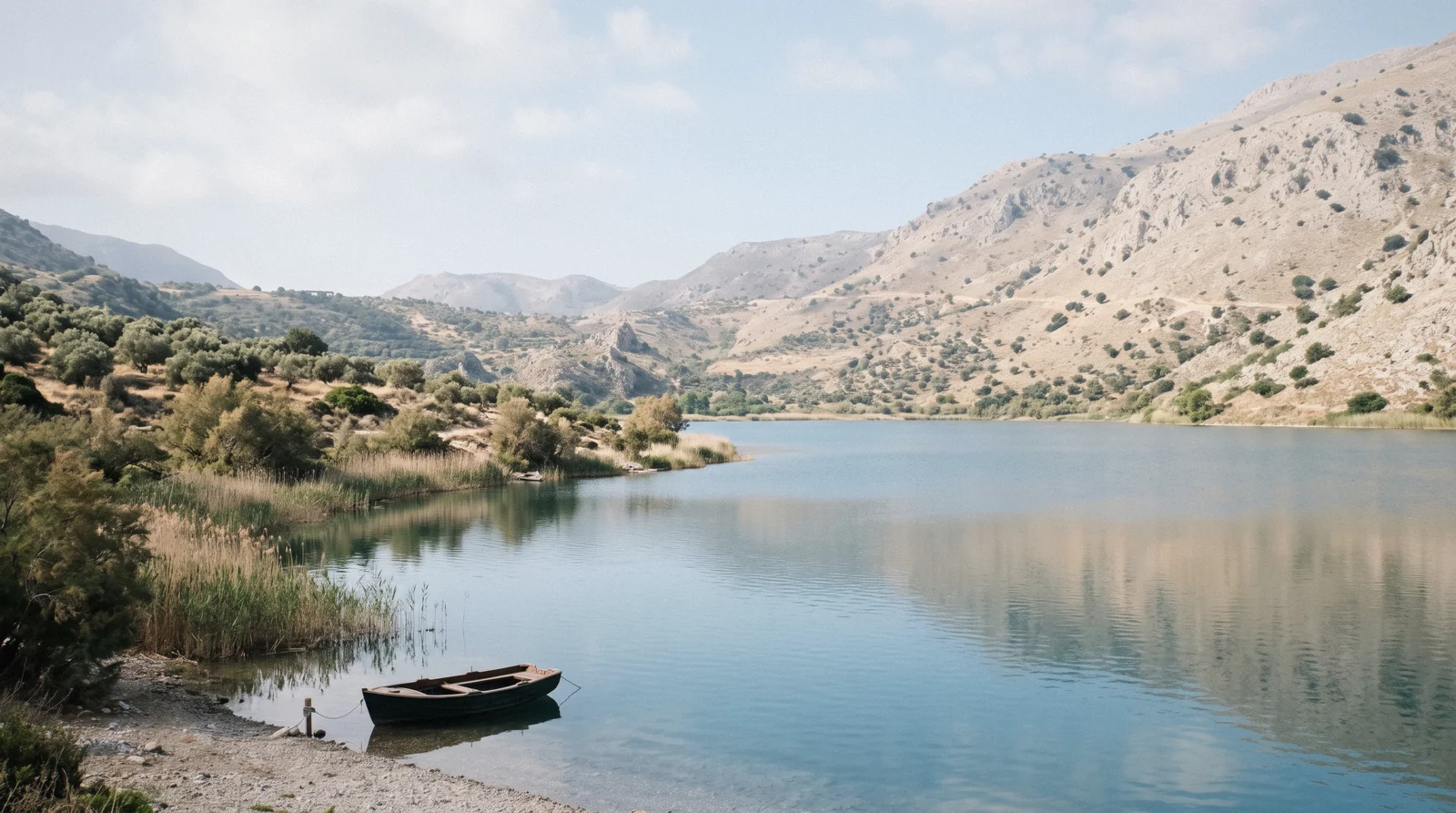 Still blue-green water of Lake Kournas ringed by pale hills, Crete
