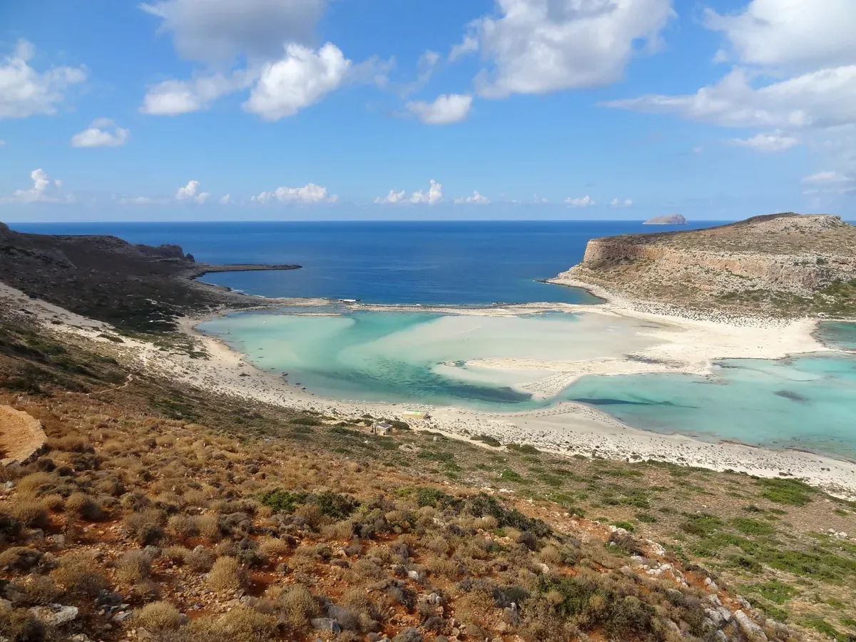 The white sandbar and shallow turquoise water of Balos lagoon from the path above, one of the two beaches in the balos or elafonisi decision